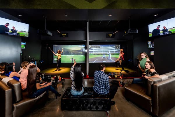 Woman and man competing in head-to-head baseball in Topgolf Swing Suite