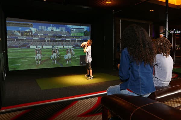 Young boy gets ready to throw a football in Topgolf Swing Suite